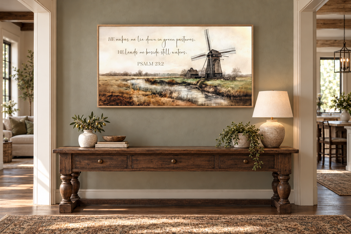 Psalm 23:2 scripture wall art featuring a windmill landscape above a rustic wooden console table.