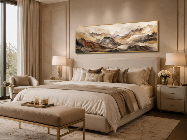 Long horizontal abstract mountain wall art in brown and gold tones above a beige bed.