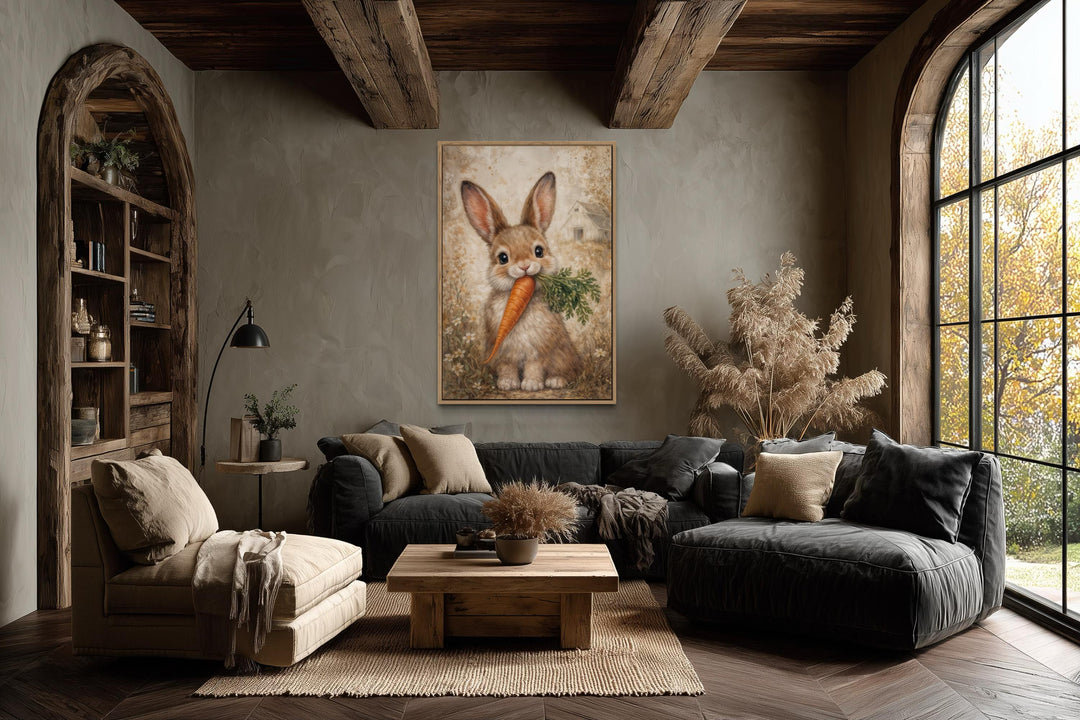 A framed canvas print of a neutral-toned bunny holding a carrot in a rustic farmhouse living room.