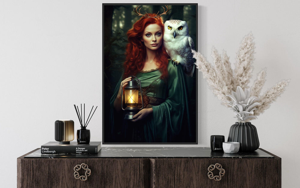 Framed canvas art of an antlered woman with red hair and a white owl, holding a glowing lantern.
