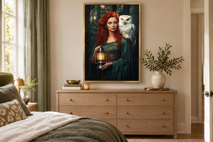 Framed canvas art of Elen of the Ways goddess with antlers, a white owl, and lantern in a bedroom.