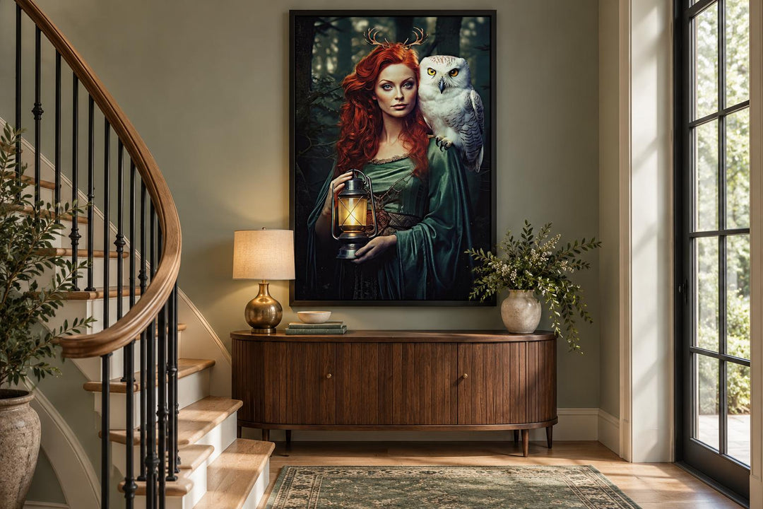 Framed canvas art of Elen of the Ways goddess with an owl and lantern above a wooden sideboard.