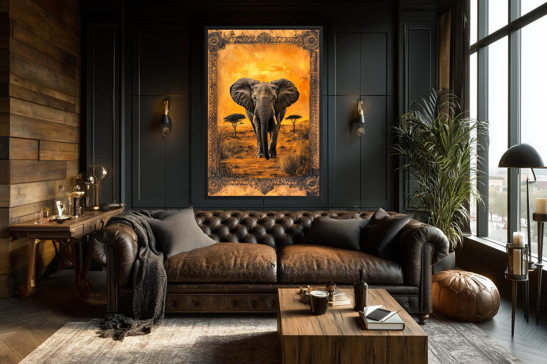 A large canvas print of an elephant in the African savanna at sunset hangs in a dark, moody room.