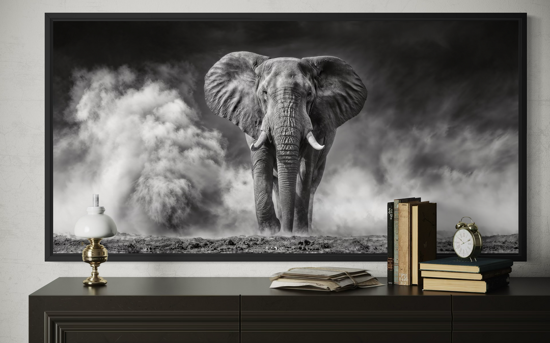 Black and white framed canvas print of an elephant in a dust cloud, displayed above a dark dresser.