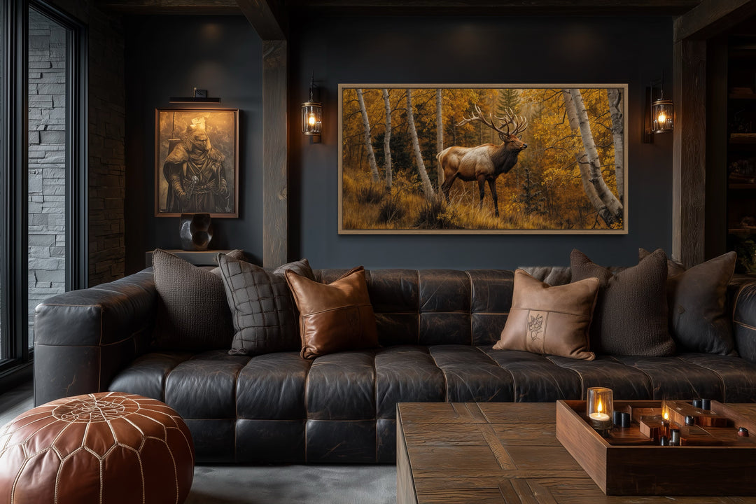 Framed canvas wall art of a majestic elk in a golden autumn birch forest above a leather sofa.