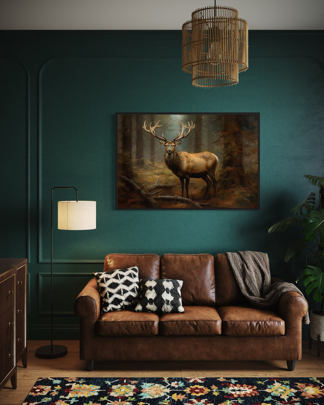 Framed canvas wall art of a majestic elk in a fir tree forest above a brown leather sofa.