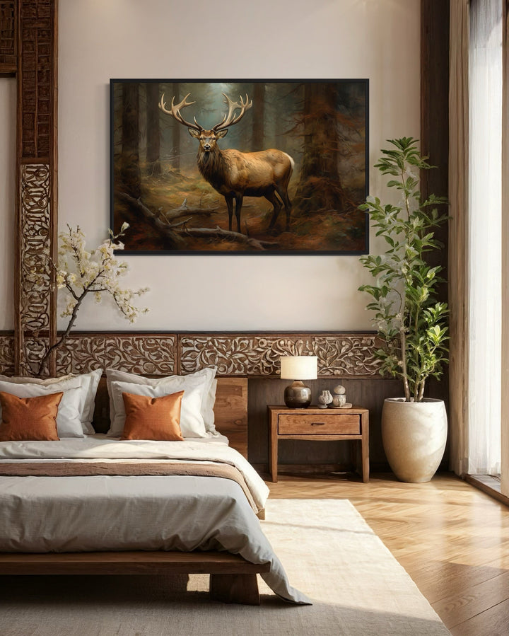 Framed canvas wall art of a majestic elk in a fir tree forest hanging above a bed in a rustic room.