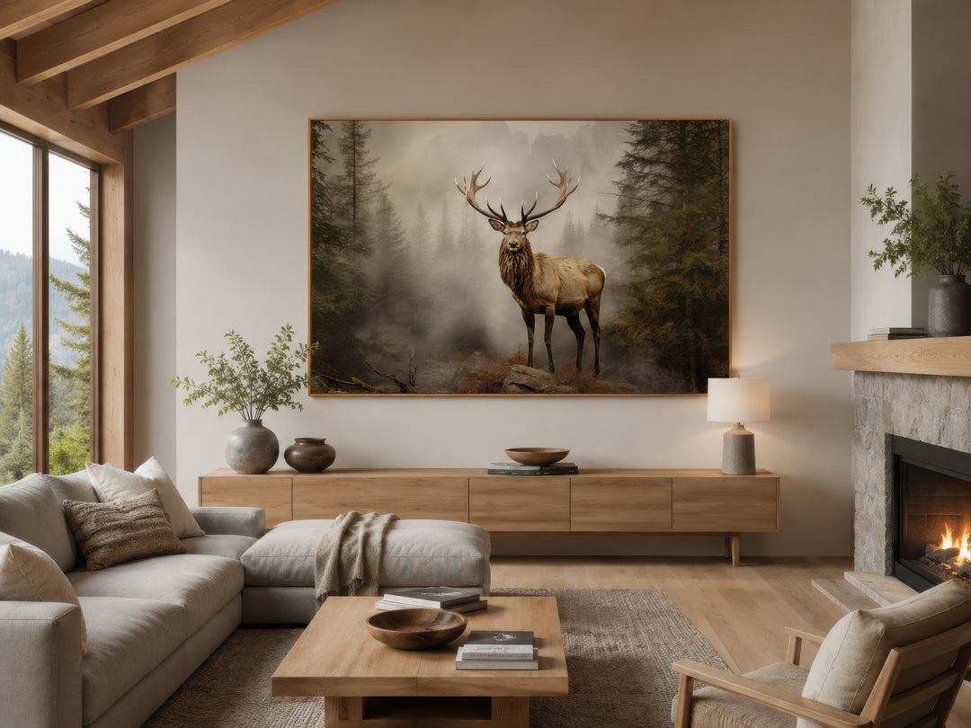 Elk in a misty fir tree forest painting in a thin gold frame above a wooden console table.