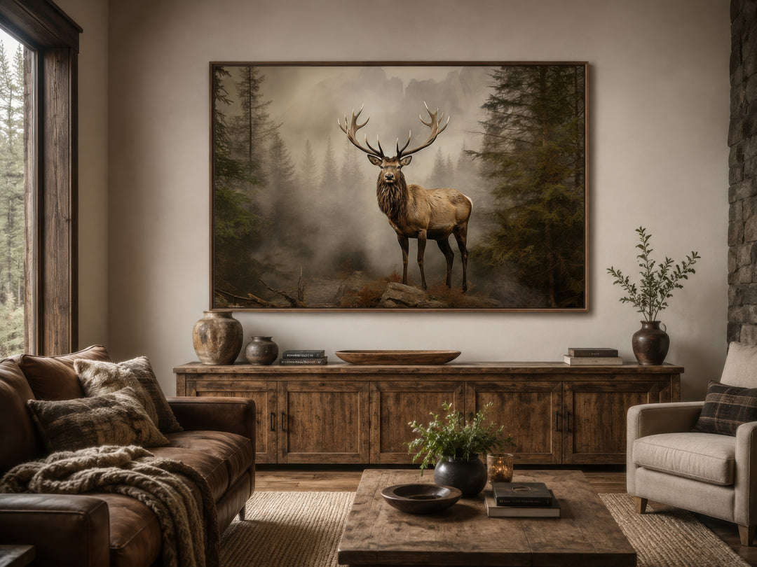 Elk in a misty fir tree forest painting in a rustic living room above a wooden sideboard.