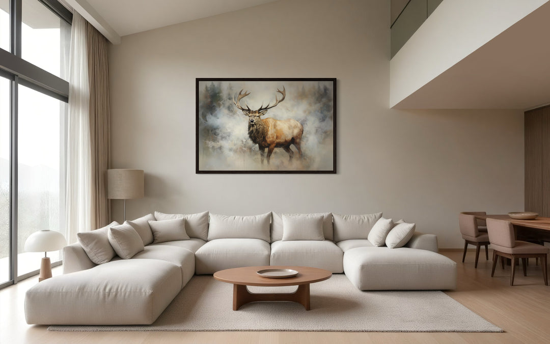 Framed canvas wall art of a majestic elk in a smoky forest above a modern sectional sofa.