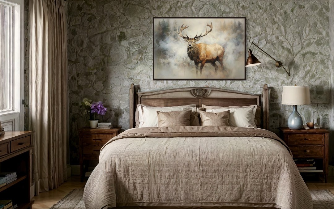 Framed canvas wall art of a majestic elk in a smoky forest above a bed in a rustic stone room.