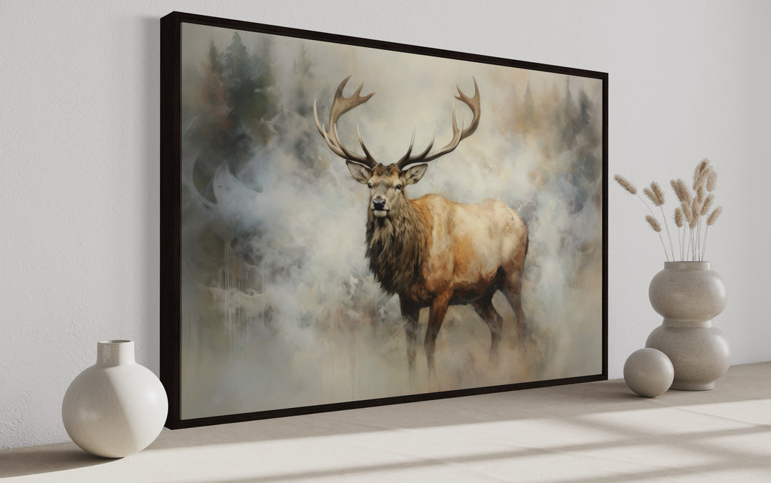 Framed canvas wall art of a majestic elk in a misty, smoky forest with neutral vases on a shelf.