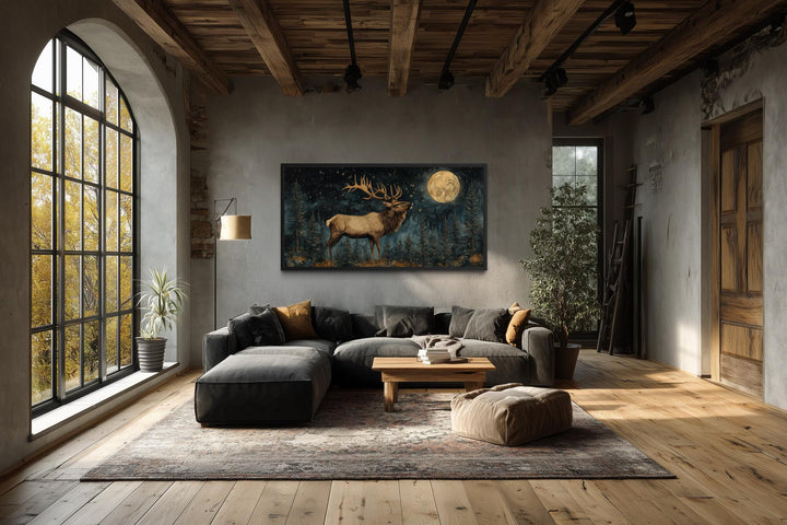 Horizontal wall art of an elk in a moonlit forest hanging in a rustic, industrial-style living room.