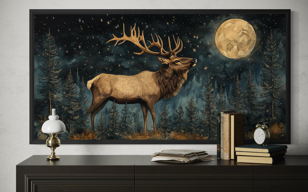 Framed wall art of a majestic elk in a moonlit forest, displayed above a rustic console table.