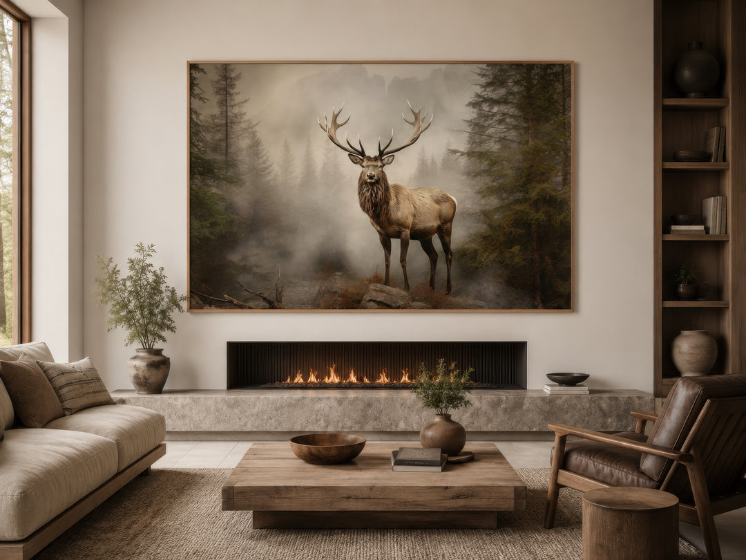 Elk in misty fir tree forest painting displayed above a modern fireplace in a rustic living room.