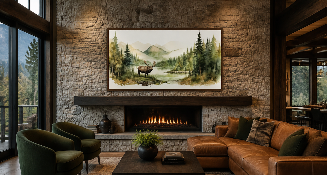 Framed watercolor elk mountain forest art hanging above a fireplace in a rustic living room.