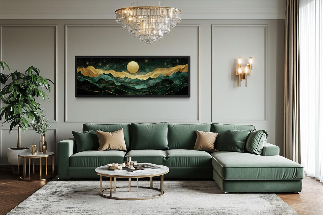 Emerald green panoramic wall art featuring gold mountains and a moon above a green velvet sofa.