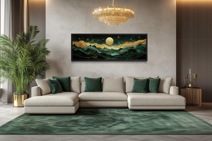 Panoramic emerald green and gold mountain wall art with a moon above a modern cream sectional sofa.