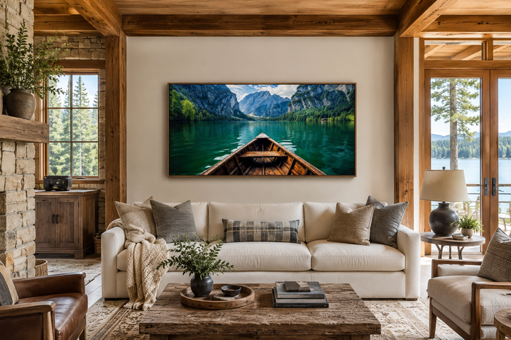 Framed wall art of a wooden boat on an emerald green lake, displayed above a white sofa.