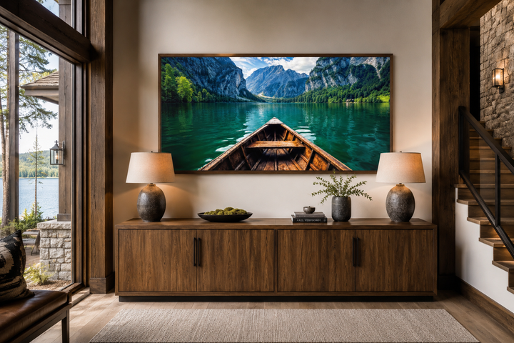 Framed wall art of a wooden boat on an emerald green lake, displayed above a wooden sideboard.