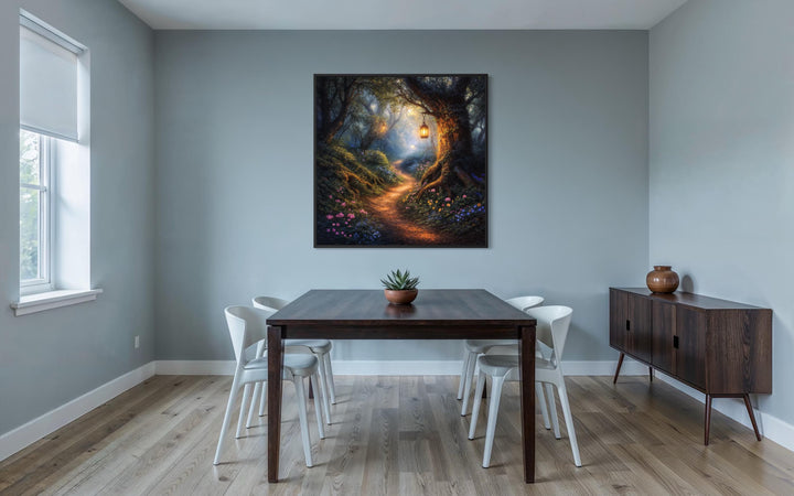 A framed canvas print of a magical woodland path with a glowing tree in a modern dining room.