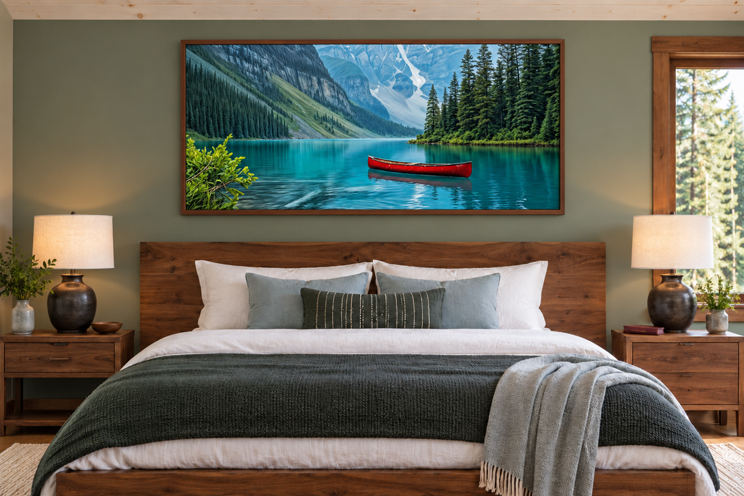 Framed canvas wall art of Lake Louise with a red canoe, hanging above a bed in a rustic bedroom.