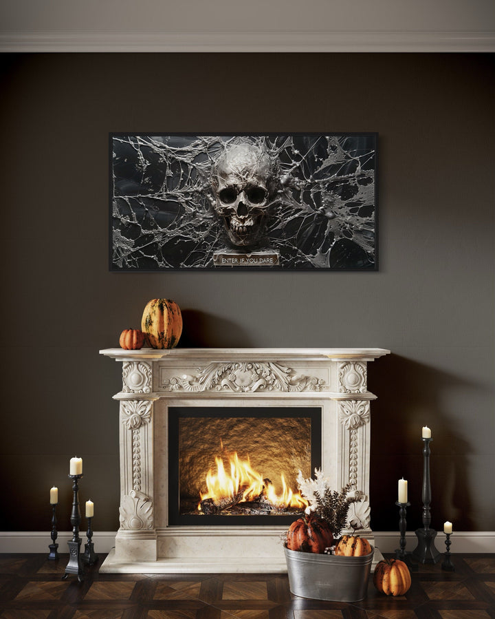 Gothic skull wall art with spiderwebs above a fireplace with pumpkins and candles.