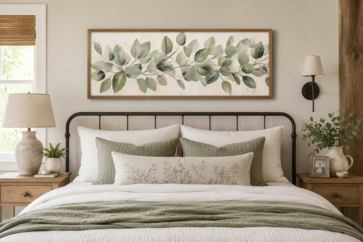 Eucalyptus leaves painted on rustic wood long horizontal framed canvas wall art above a bed.