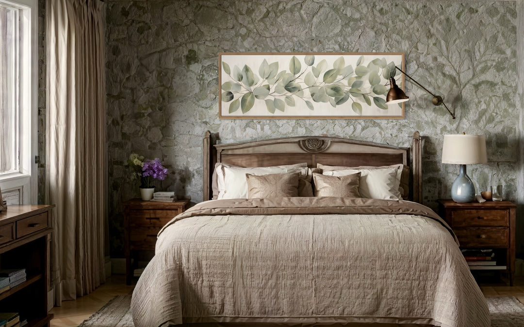 Eucalyptus leaves painted on rustic wood long horizontal framed canvas wall art above a bed.