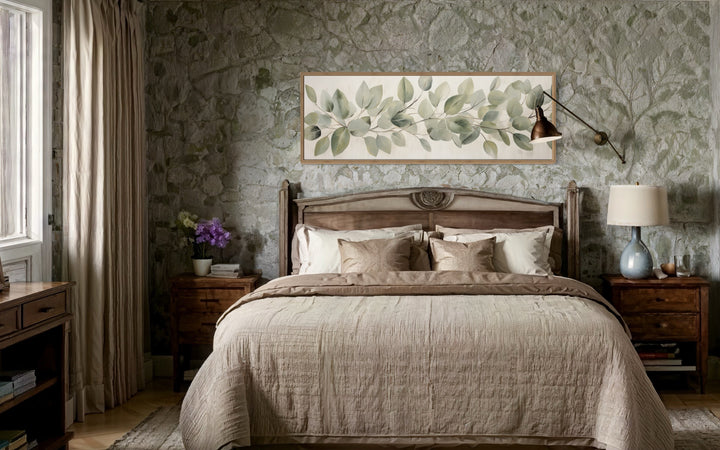 Eucalyptus leaves painted on rustic wood long horizontal framed canvas wall art above a bed.