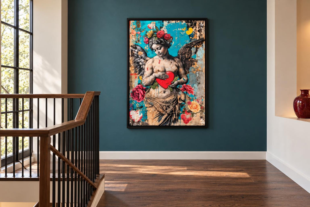 Fallen Angel Graffiti Modern Wall Art featuring a winged statue holding a red heart on a teal wall.