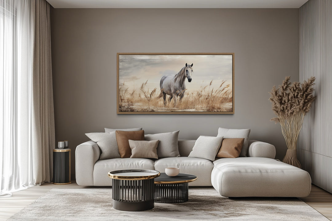 Farm horse in a wheat field framed canvas wall art above a modern sofa in a neutral living room.
