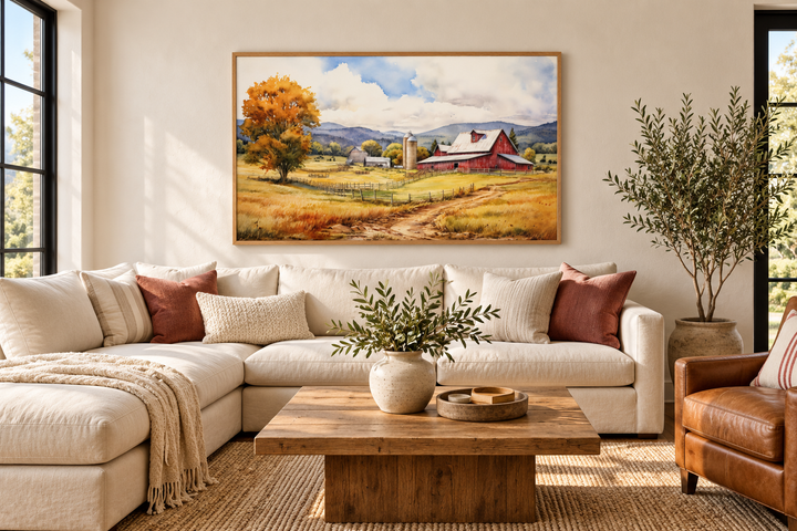 Farm scene painting with a red barn and golden fields in a wood frame above a white sectional sofa.