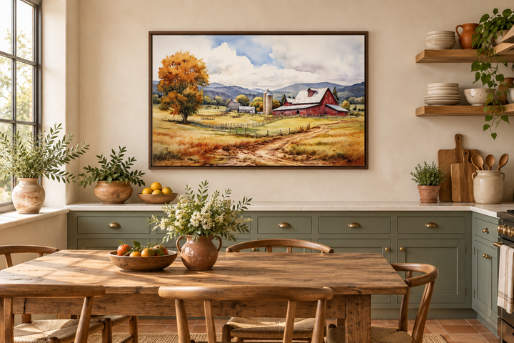 Framed watercolor painting of a red barn in a golden field above a rustic kitchen dining table.