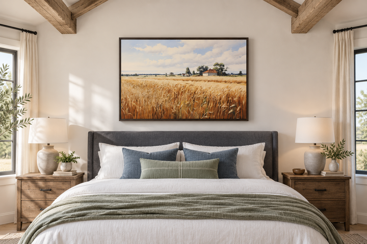 Rustic wheat field landscape framed canvas wall art hanging above a bed in a farmhouse bedroom.