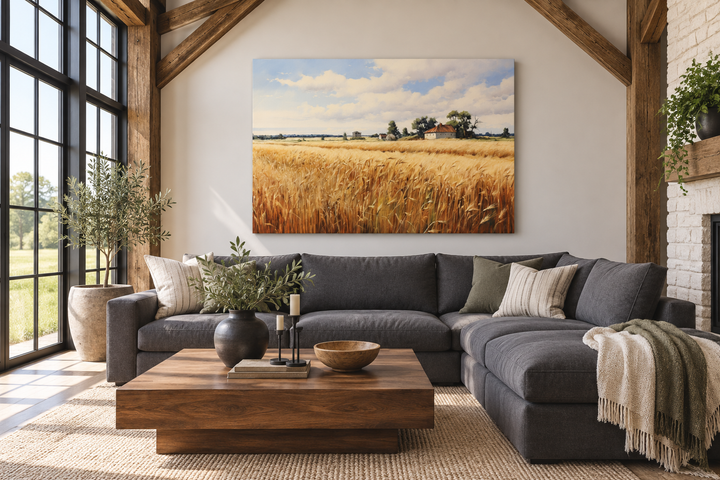 Rustic wheat field landscape canvas wall art hanging above a dark grey sectional sofa.