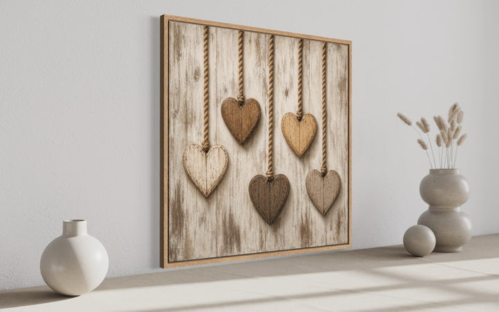 Rustic heart canvas wall art featuring five wooden hearts hanging on a whitewashed wood background.