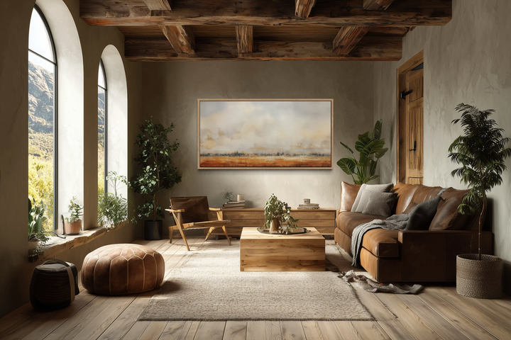 Minimalist farm field canvas painting in neutral tones above a wooden console in a rustic room.