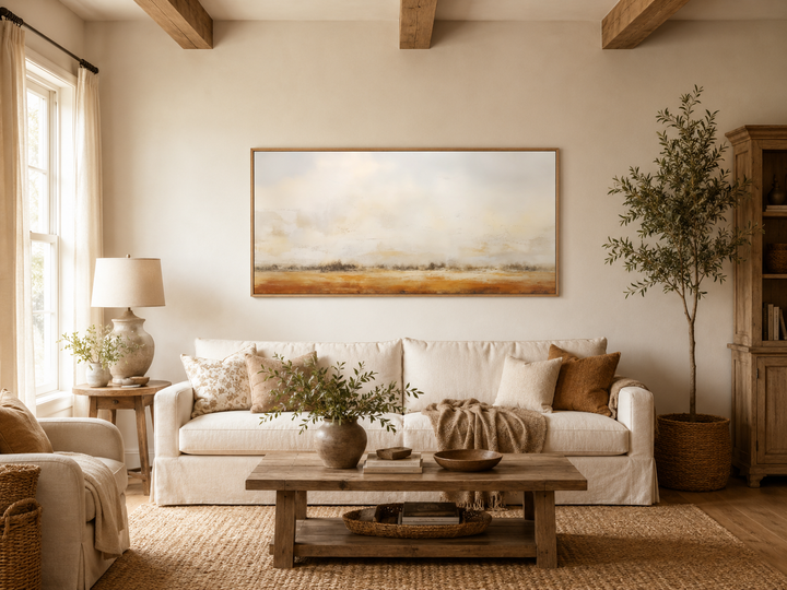 Minimalist farmhouse canvas art featuring a neutral rustic farm field painting above a white sofa.