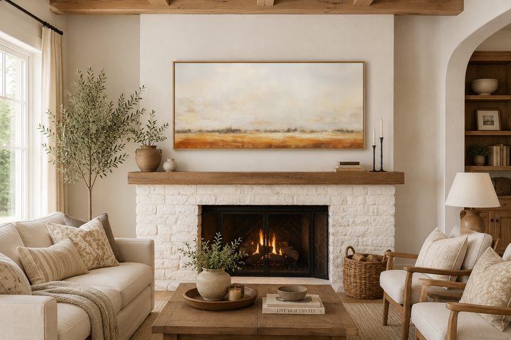 Minimalist farm field painting in neutral tones above a white brick fireplace in a rustic room.