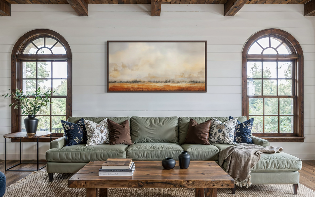 Minimalist farm field canvas art in neutral tones hanging above a green sofa in a rustic living room.