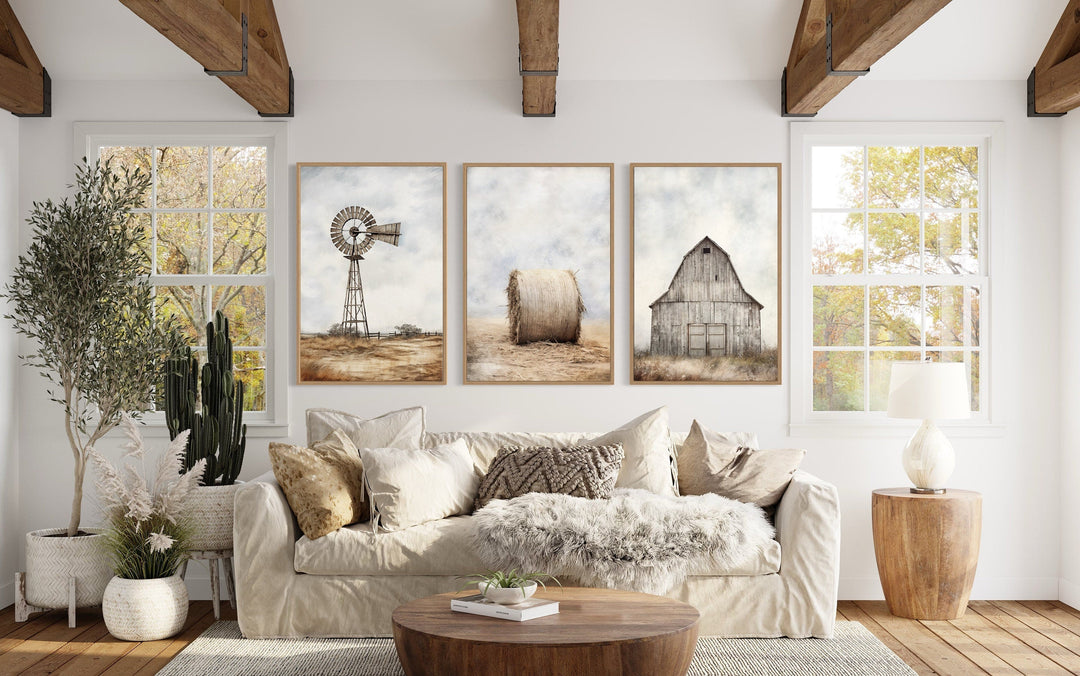 Set of three rustic farmhouse prints featuring a windmill, hay bale, and barn above a beige sofa.