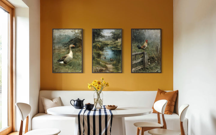 Three framed farmhouse paintings of a goose, ducks, and a rooster on a yellow wall above a table.