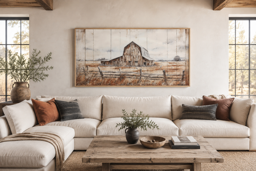 Rustic barn wall art featuring a weathered barn in a field, framed above a white sectional sofa.
