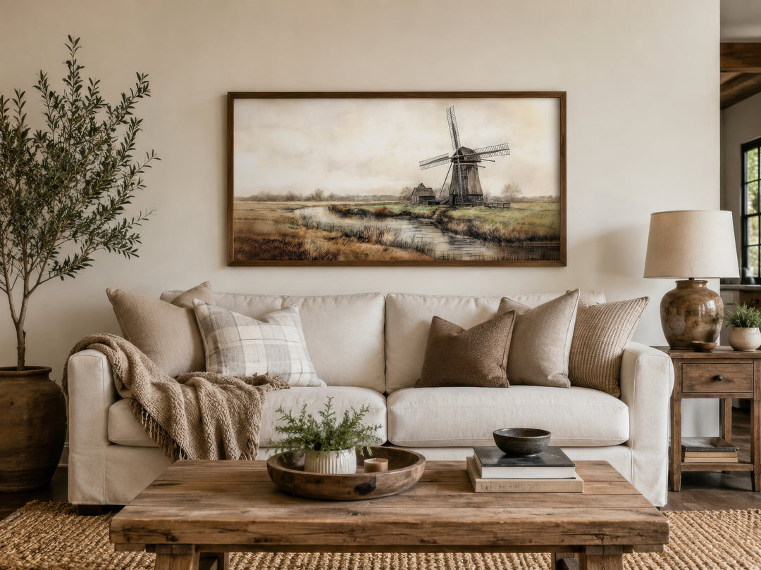 Vintage windmill wall art in a wooden frame above a white sofa in a rustic farmhouse living room.