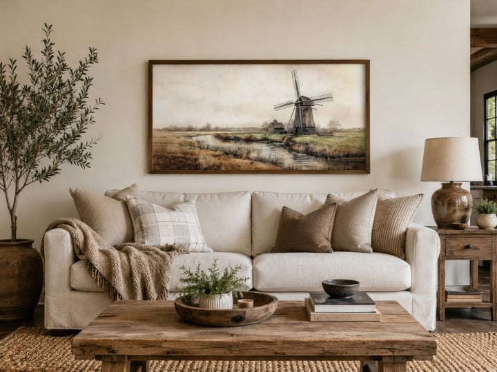Vintage windmill wall art in a wooden frame above a white sofa in a rustic farmhouse living room.