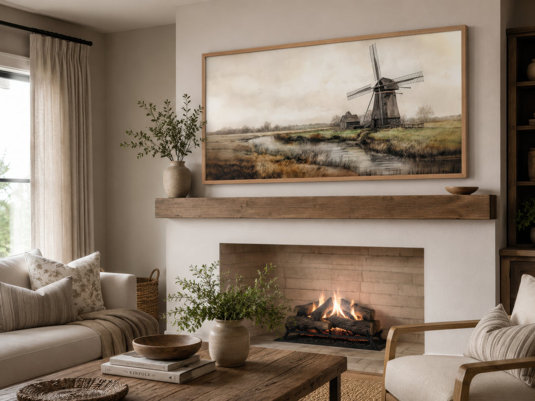 Vintage windmill canvas print in a light wood frame hanging above a rustic fireplace mantel.