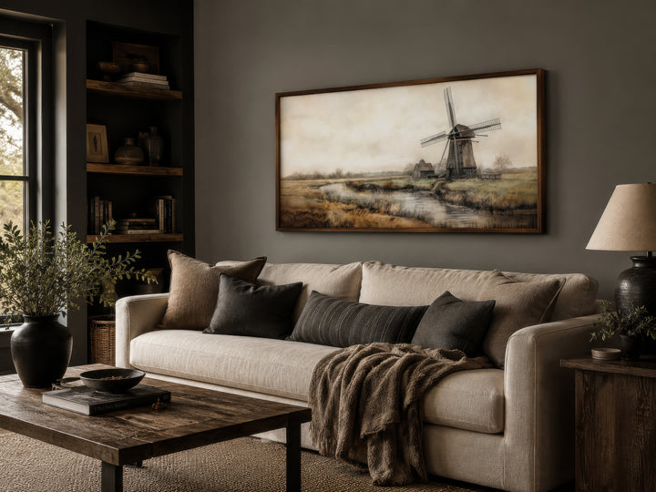 Framed vintage windmill canvas print hanging above a cream sofa in a rustic living room.