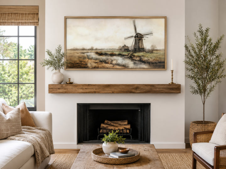 Vintage windmill canvas print in a wooden frame hanging above a rustic fireplace mantel.
