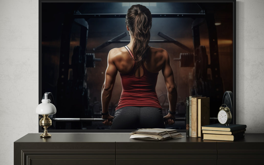 Motivational canvas art of a strong woman lifting a barbell in a gym, displayed above a sideboard.